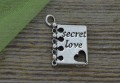 307197 Zawieszka mała książka z napisem secret love w kolorze srebrnym